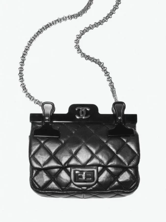 Black Chanel quilted handbag with metal chain strap and top clasp closure against a white background in a studio product shot.