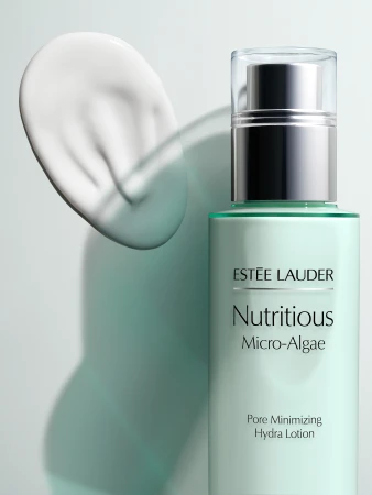 Estee Lauder Nutritious Micro-Algae Pore Minimizing Hydra Lotion is displayed with a smear of the product on a light green background.