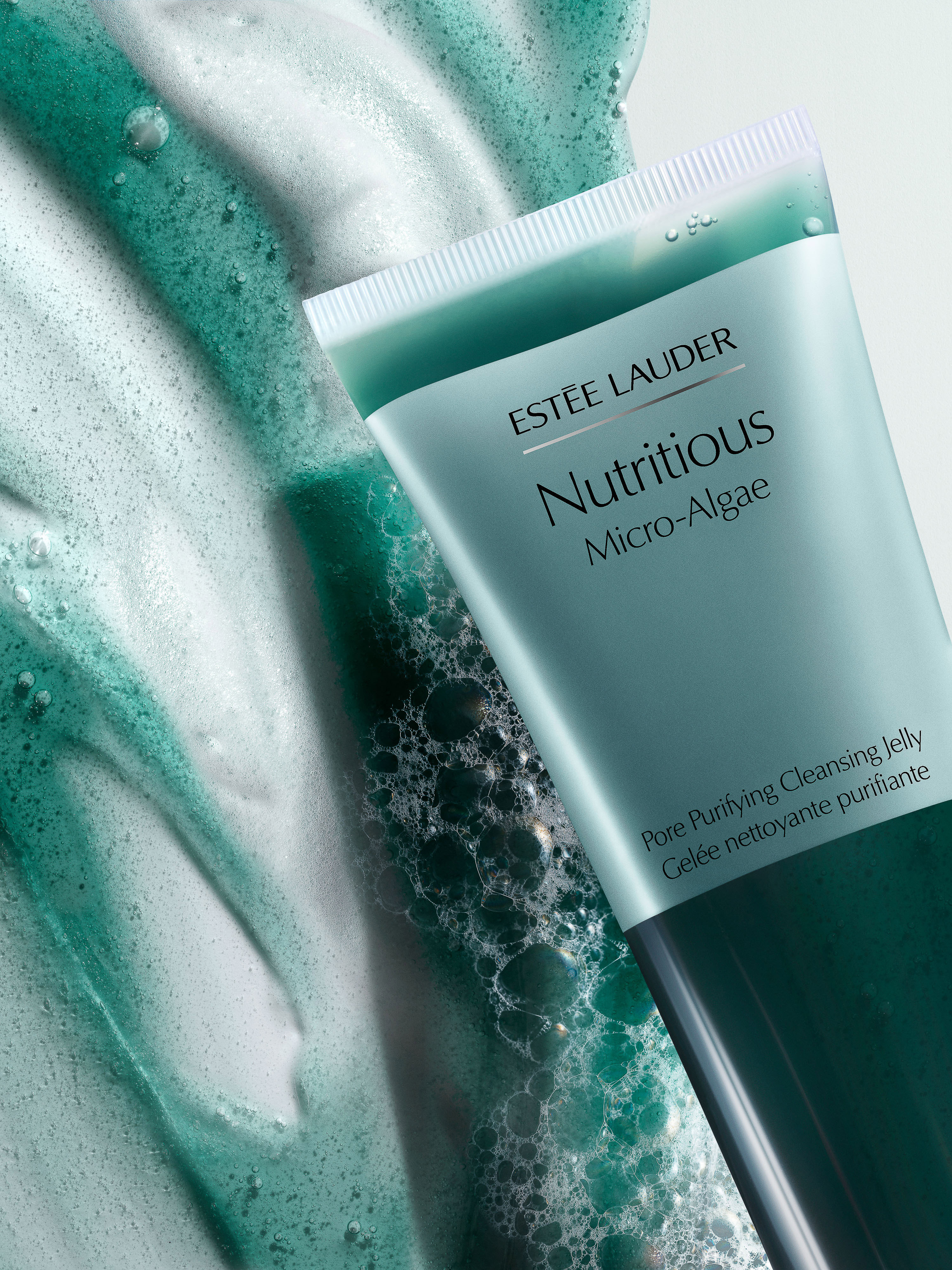 Estee Lauder Nutritious Micro-Algae cleanser in a tube surrounded by a frothy green and white algae-based cleanser.