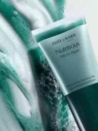Estee Lauder Nutritious Micro-Algae cleansing jelly tube next to green foaming cleanser texture against white background