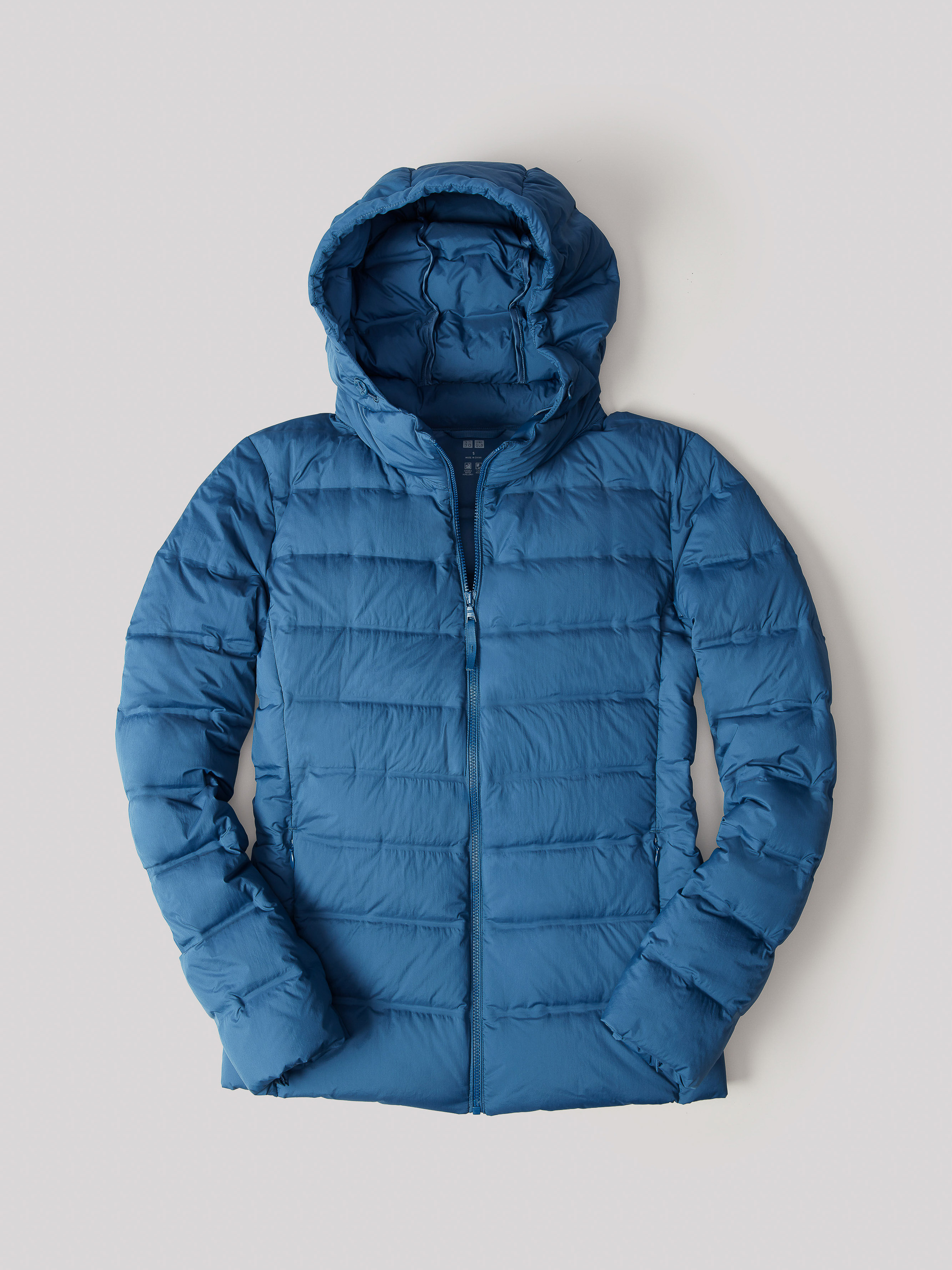 Blue hooded puffer jacket isolated on a neutral background, featuring a quilted design, a full front zipper, and long sleeves.