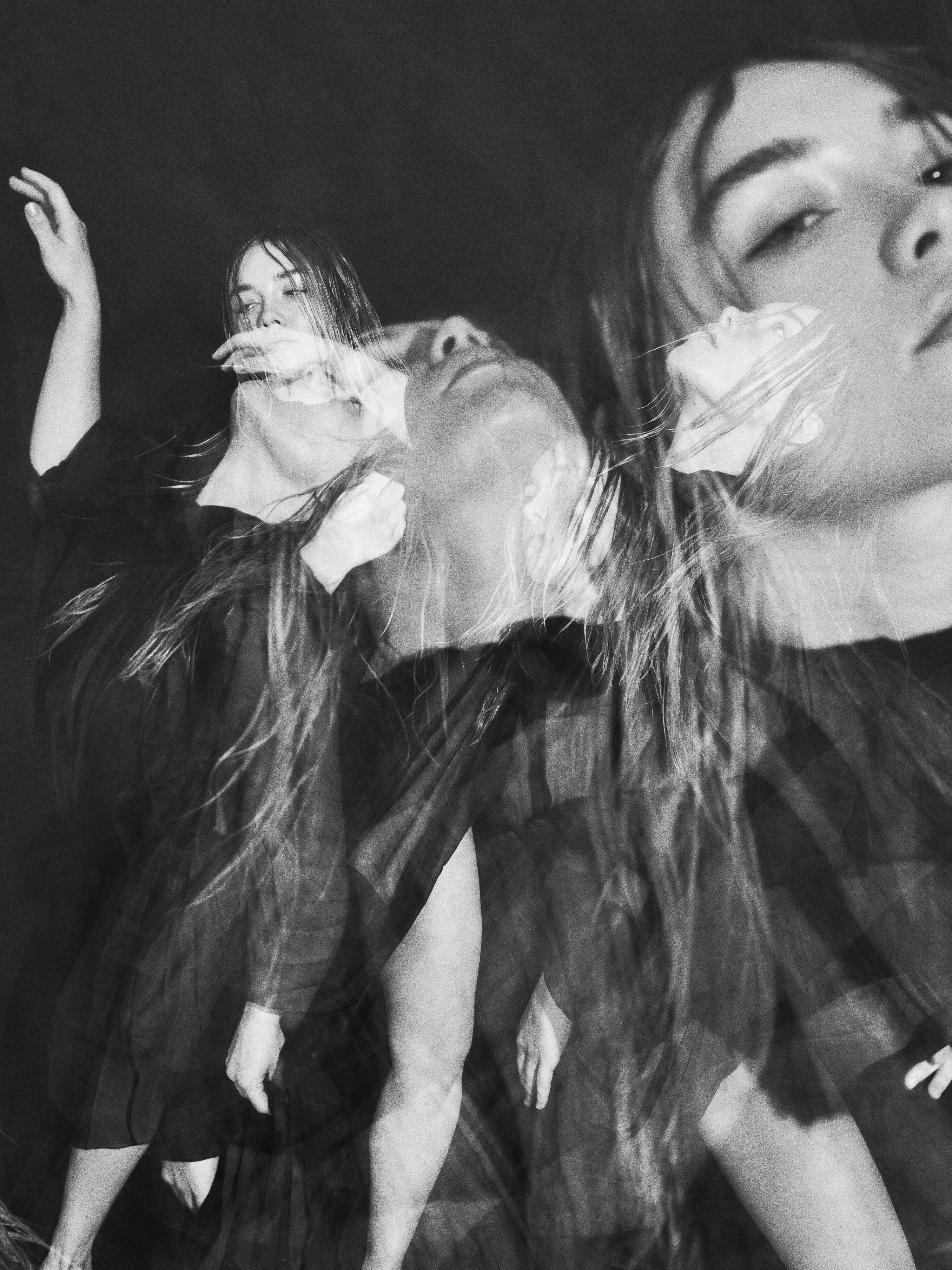 Black and white portrait features a woman with long hair in a dress, with multiple exposures creating a sense of motion and depth.
