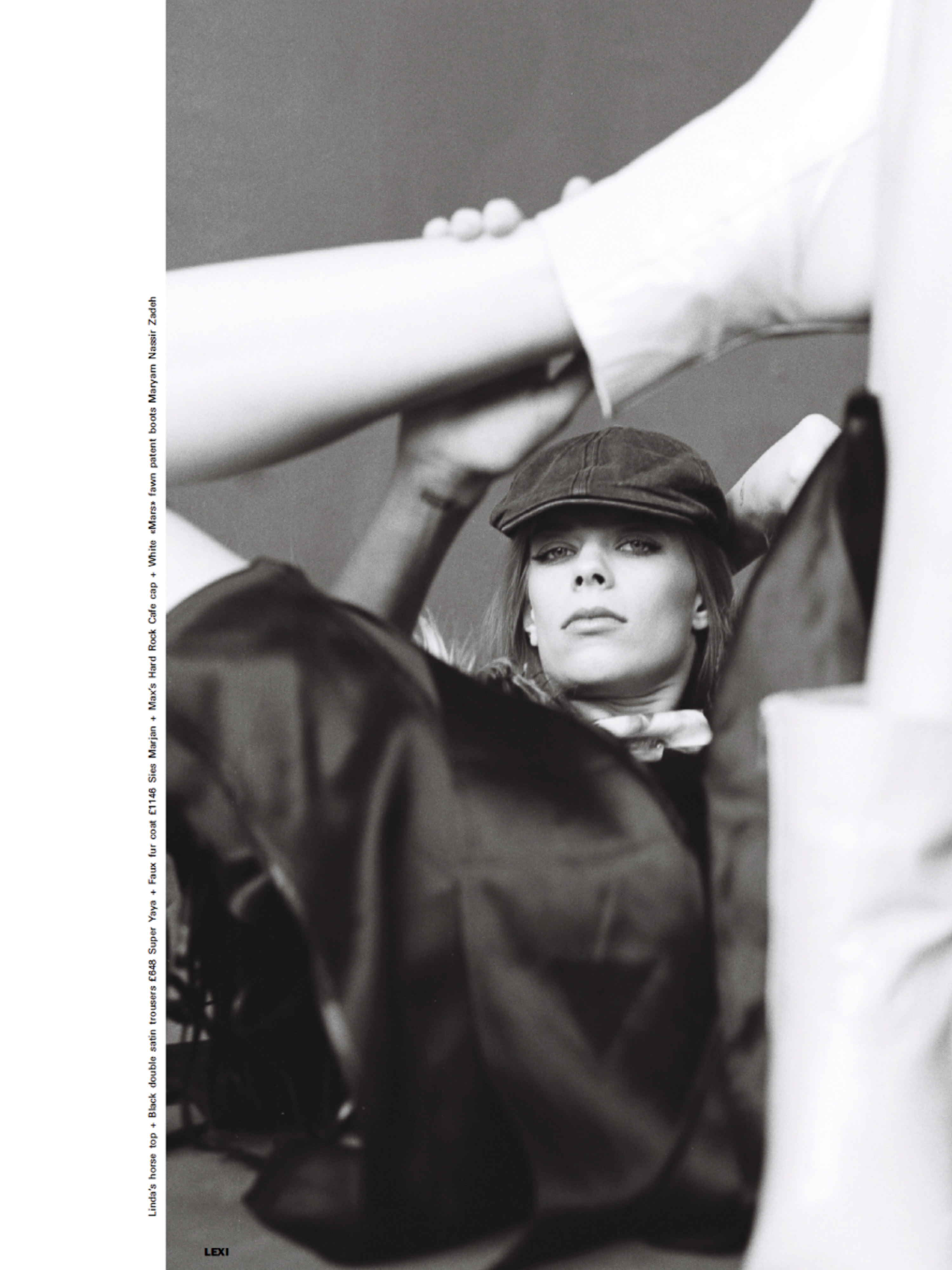 Monochrome portrait of a woman wearing a cap, staring at the camera with a serious expression, partially framed by blurry objects.