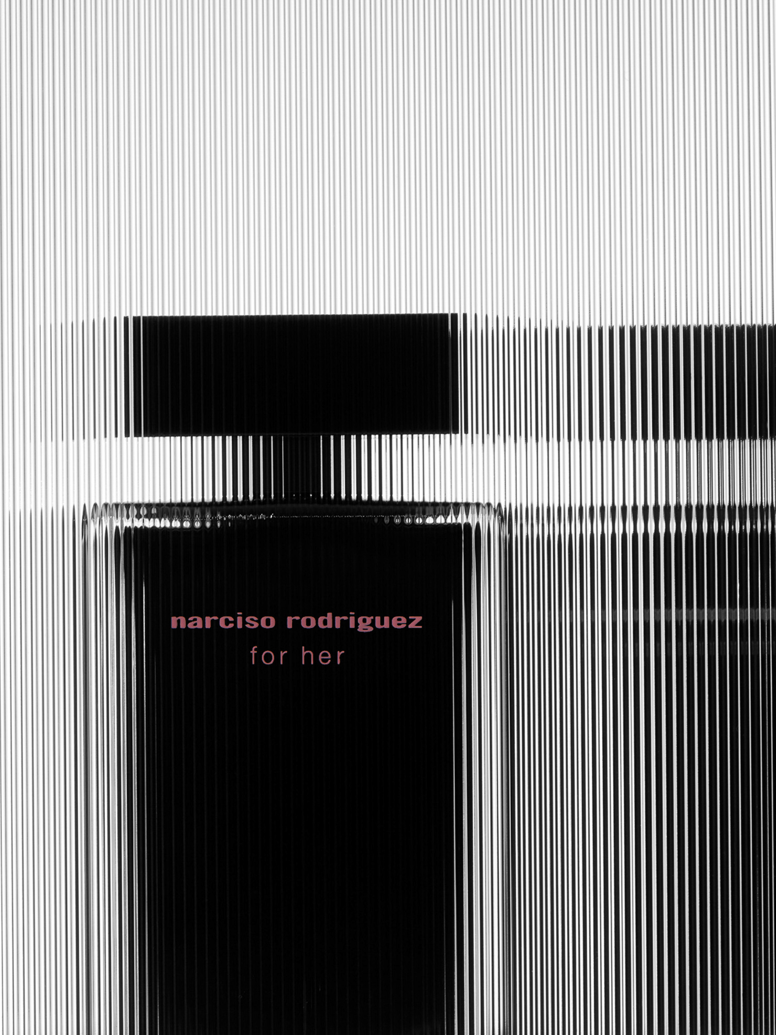 Close-up of a black Narciso Rodriguez perfume bottle with pink text against a textured white background of parallel vertical lines.