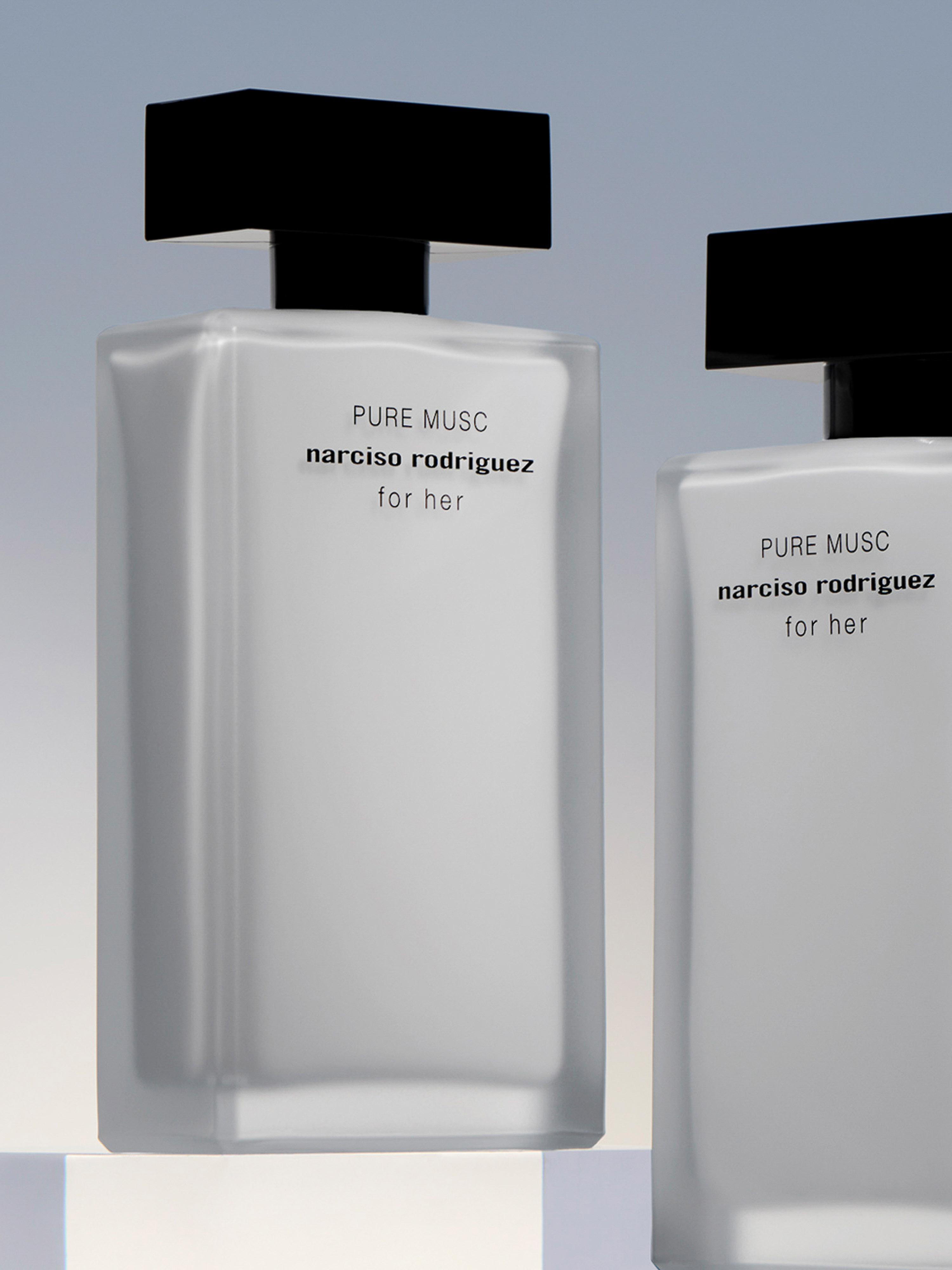 Two rectangular perfume bottles, black caps, minimalist labels, light background. Beauty product shot for fragrance advertising.