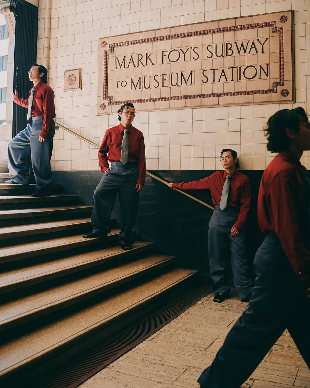 A man in a red shirt and gray pants is seen in a repeating pattern in a subway station, standing on stairs near station signage.