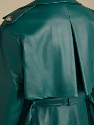 Close-up back view of a dark green leather trench coat with buttoned shoulder epaulette and belted waist.