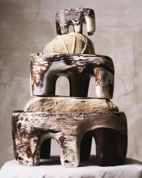 Stacked stack of swirled brown and white resin objects and natural stone elements against a textured background