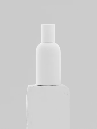 Minimalist white bottle sits atop a rough white block against a soft white background, creating a clean, modern aesthetic.