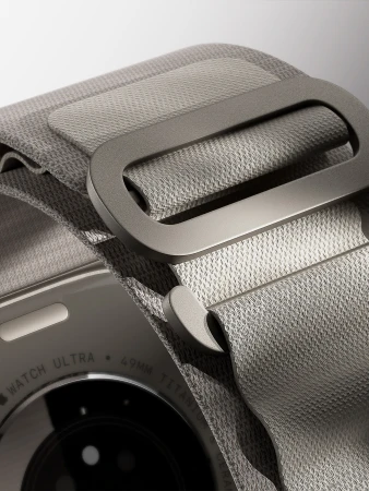 Close-up of an Apple Watch Ultra with a gray woven band, showcasing the device's design and texture on a white background.