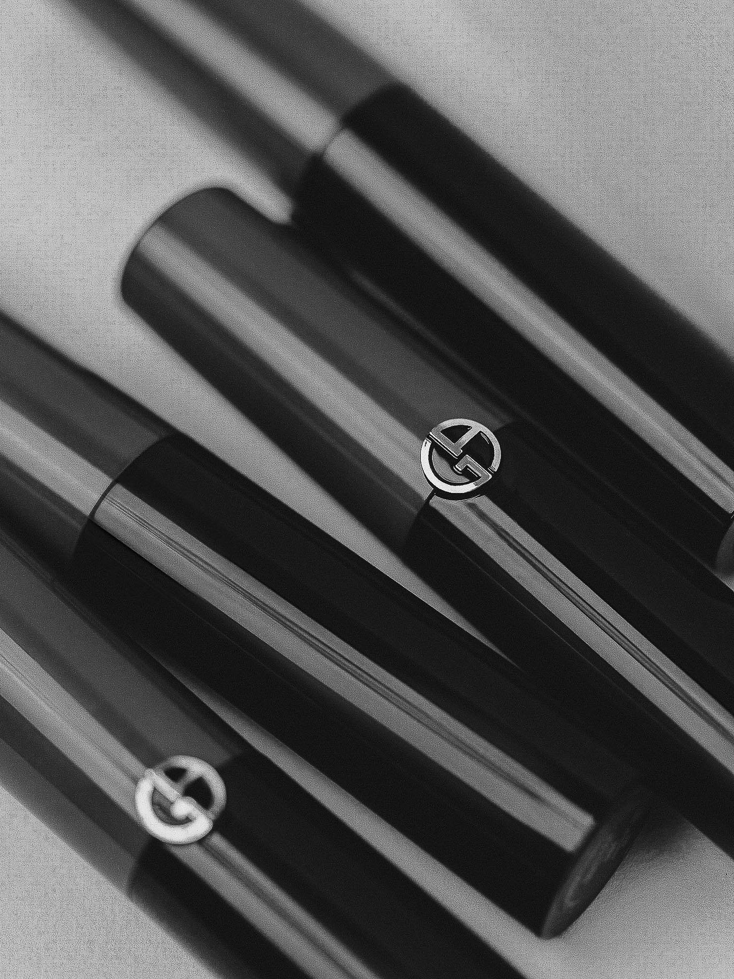 Close-up of arranged black and metallic Giorgio Armani lipstick tubes in studio, reflecting luxury and beauty for cosmetics promotion.