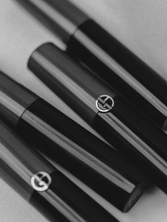 Close-up of arranged black and metallic Giorgio Armani lipstick tubes in studio, reflecting luxury and beauty for cosmetics promotion.