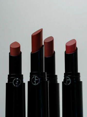 Four Giorgio Armani lipsticks in a row against a light background, showcasing different shades of color in a product shot.