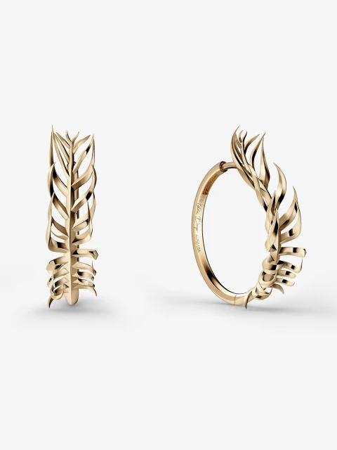 Close-up of two gold hoop earrings with leaf-shaped designs on a white background, showcasing fine jewelry and metalwork.