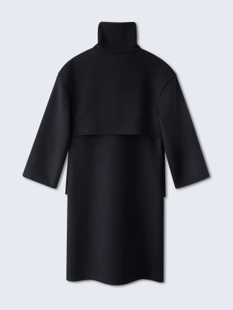 Back view of a black dress with a high collar and long sleeves, set against a neutral background in a studio photography setting.