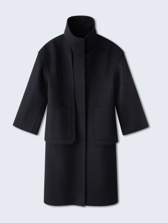 Studio shot of a black wool coat, featuring a high collar and boxy silhouette, set against a gradient blue backdrop. Minimalist fashion.