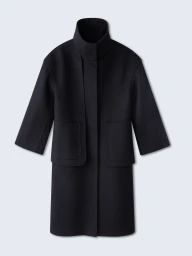 Black structured high-collar outerwear coat with layered front panels and patch pockets on a pale studio background.