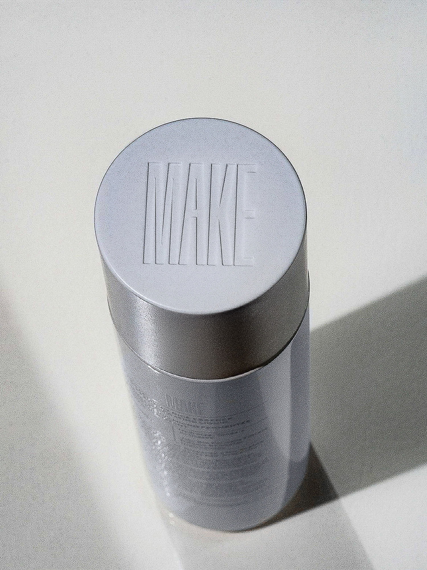Elevated shot of a gray cylindrical container with a white lid, label with small text, and the word 'WAKE' embossed on the lid.