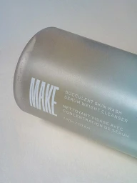 Close-up of a Make Beauty Succulent Skin Wash frosted cleanser bottle against a light neutral background.