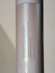 Close-up of Make Beauty Micro Ferment Rice Essence bottle showing pearlescent shimmer finish and printed product text.