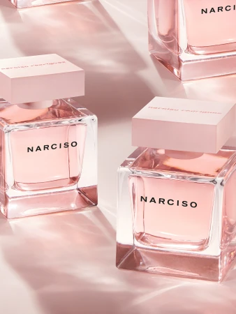 Multiple Narciso Rodriguez perfume bottles with pink lids and clear glass on a pink backdrop, in a beauty and product photography style.