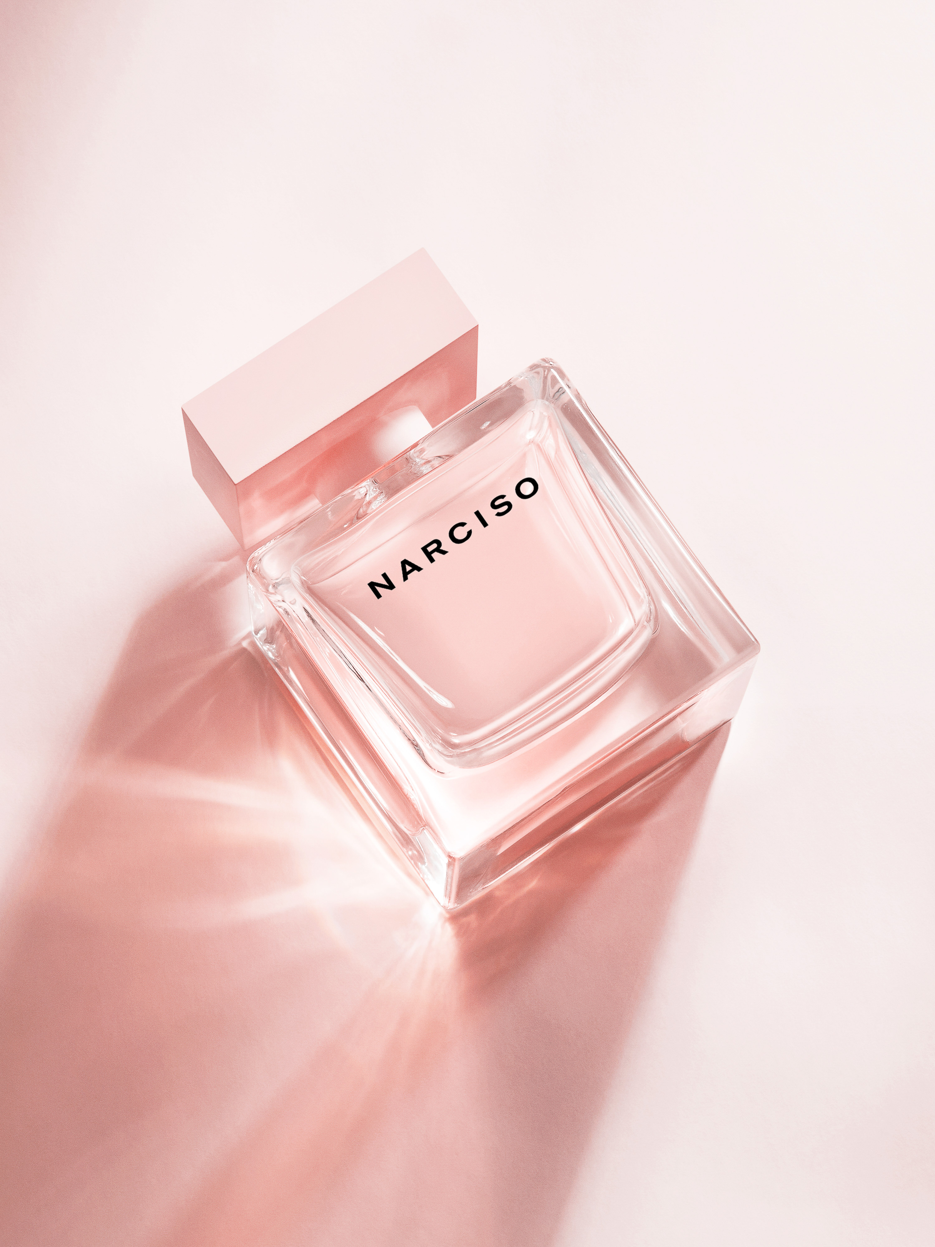 Square bottle of Narciso Rodriguez perfume on a soft pink surface with subtle shadows, minimalistic, beauty product still life.