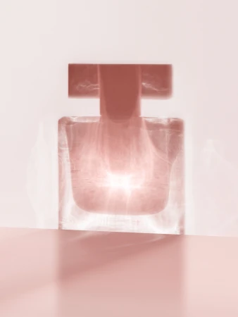 Still life of a transparent glass perfume bottle on a pink surface, capturing diffused light and soft shadows.