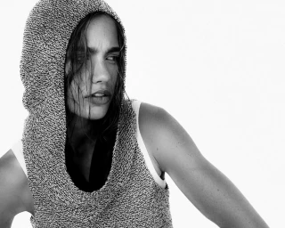 Woman wearing a textured grey knit hooded top against a bright white background for Interval Magazine