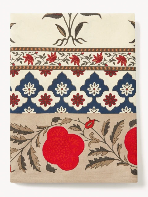 Botanical textile art featuring repeating floral patterns and leaf motifs in red, blue, and brown on a neutral background, flat lay.