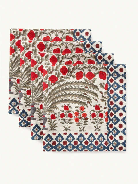 Four white napkins with a red and blue floral design on a white surface, creating a decorative textile product presentation.