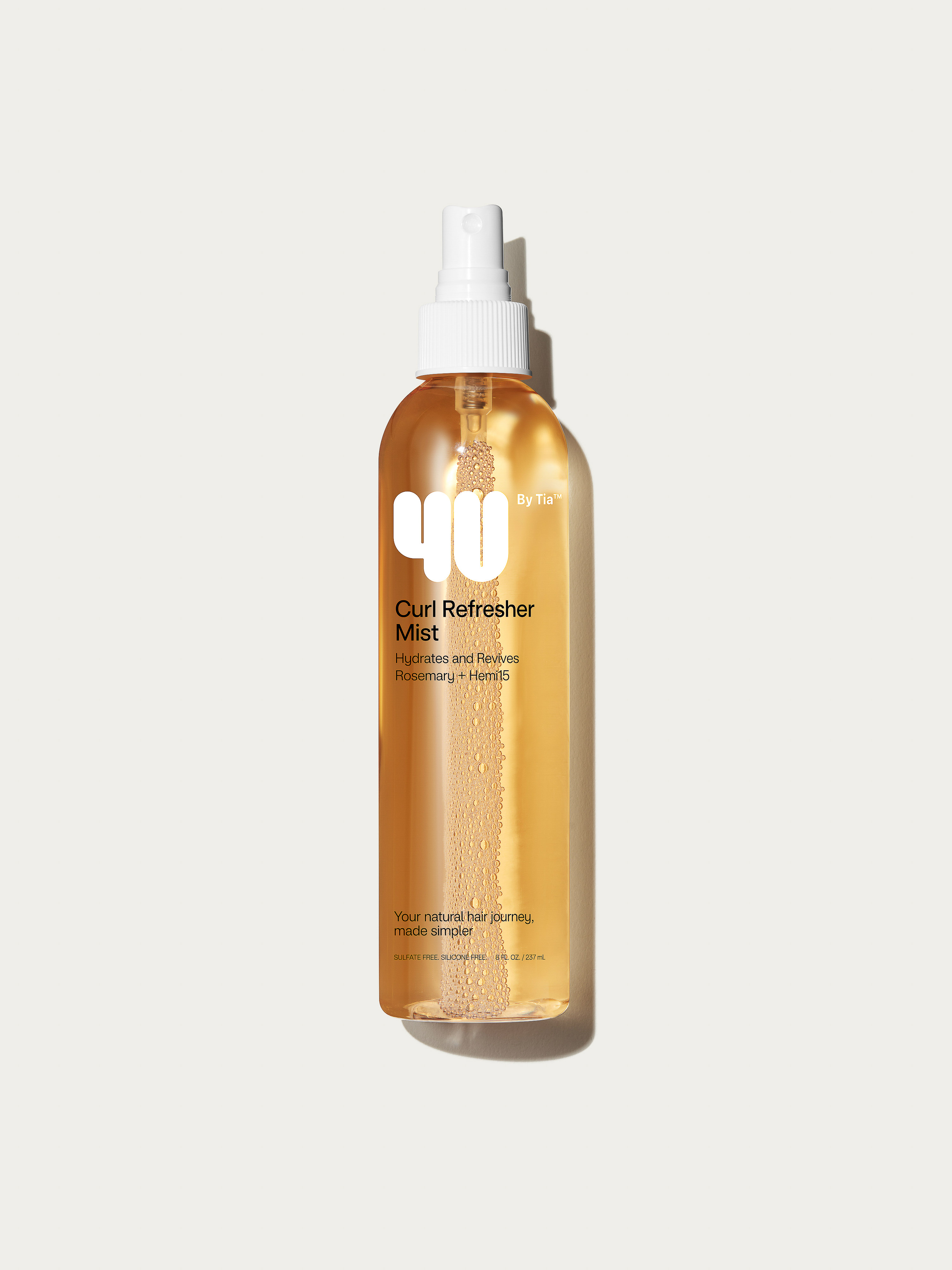 A bottle of 4U by Tia Curl Refresher Mist with a white spray nozzle is displayed on a neutral background in a studio shot.