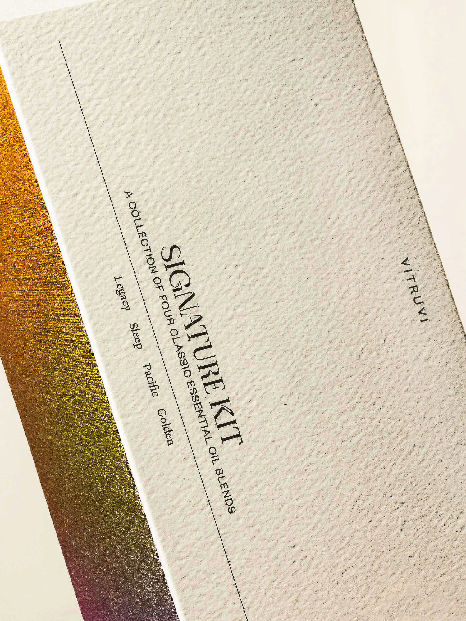 Vitruvi Signature Kit box featuring a collection of four classic essential oil blends and the brand's logo on a textured surface.