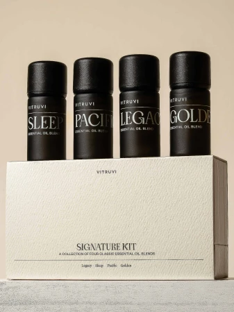 Four Vitruvi essential oil bottles on a Signature Kit box. The oils are labeled Sleep, Pacific, Legacy, and Golden.