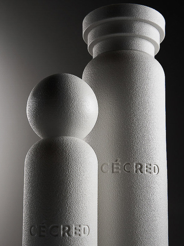Monochromatic product shot of two cylindrical objects with a textured finish and the word CECRED embossed on the front.