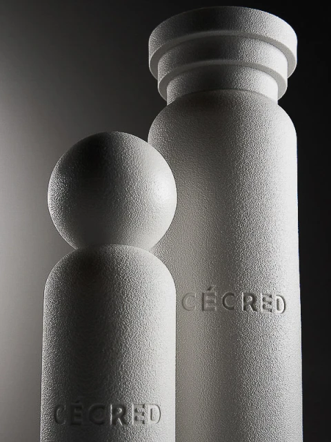 Monochromatic product shot of two cylindrical objects with a textured finish and the word CECRED embossed on the front.