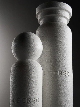 Monochromatic product shot of two cylindrical objects with a textured finish and the word CECRED embossed on the front.