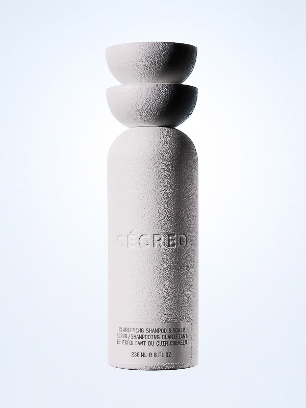 White textured CÉCRED clarifying shampoo bottle with stacked spherical lid, against a gradient background. Beauty product shot.
