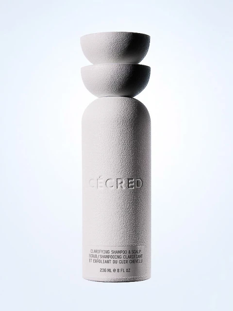 White textured CÉCRED clarifying shampoo bottle with stacked spherical lid, against a gradient background. Beauty product shot.