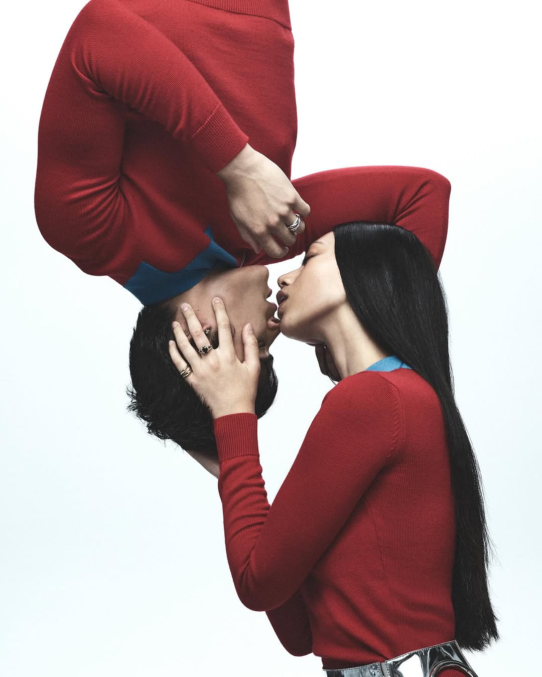 Two models wearing red sweaters in a mirrored surreal pose against a clean white background for Russh by photographer Jake Terrey.