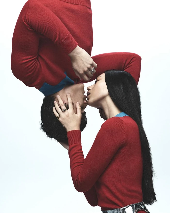 Two models wearing red sweaters in a mirrored surreal pose against a clean white background for Russh by photographer Jake Terrey.