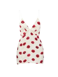 Khaite cream mini slip dress with thin spaghetti straps and an allover red lips print on a seamless white background.