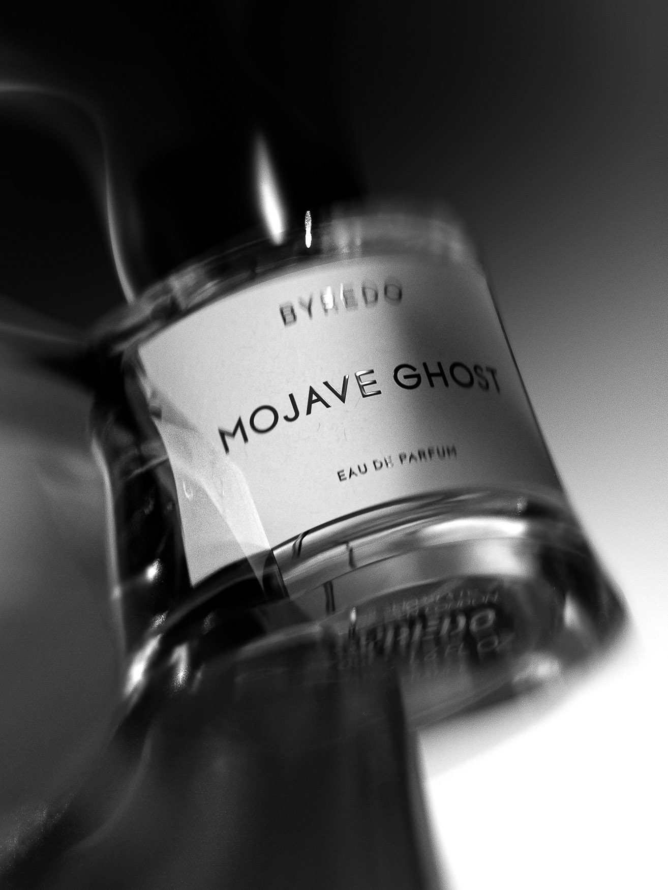 Byredo Mojave Ghost perfume bottle close-up in black and white, showcasing the brand and product name with shallow depth of field.