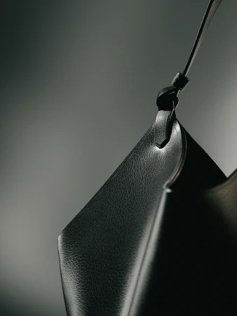 Close-up product shot of a black leather purse with a strap against a dark grey background, product photography, studio lighting.