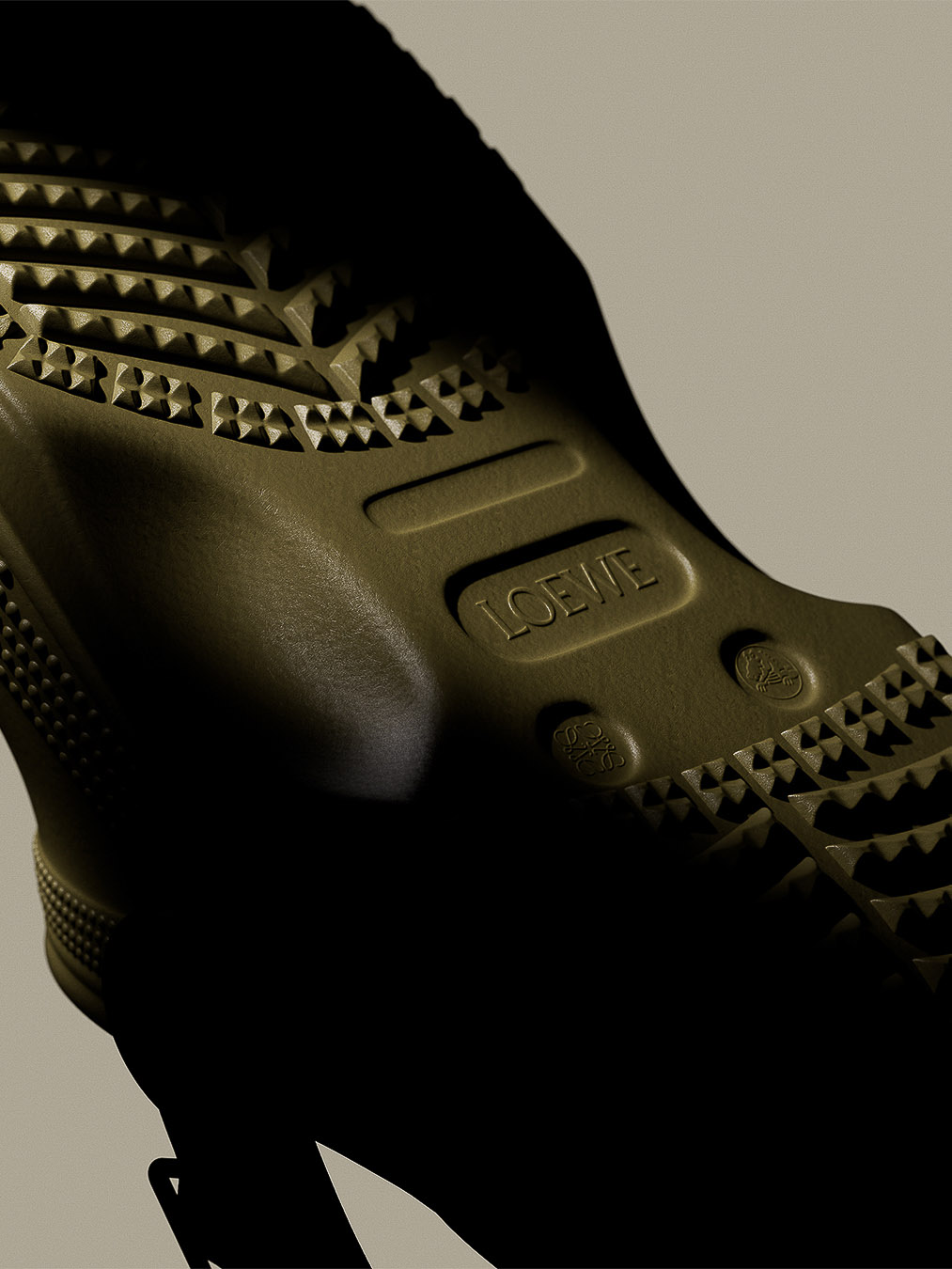 Olive green Loewe rubber boot with a deep tread and logo detail against a pale neutral background in a close-up product shot.