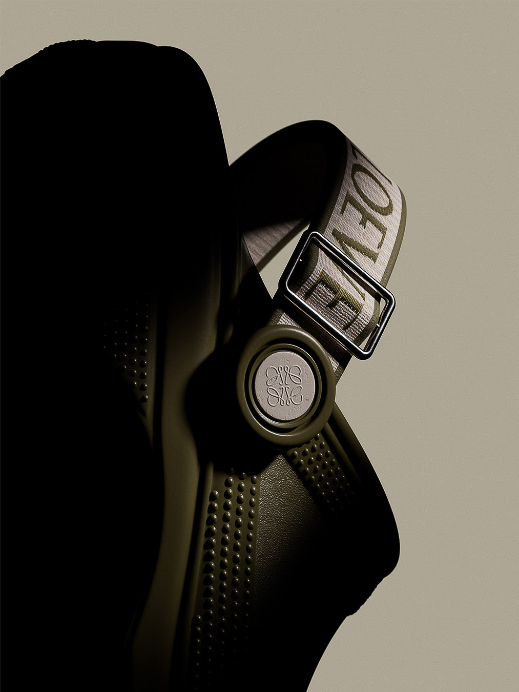 Olive-green rubber clog with embossed logo and adjustable nylon strap with metal buckle, showcased against a neutral background.