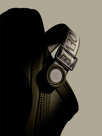 Olive-green rubber clog with embossed logo and adjustable nylon strap with metal buckle, showcased against a neutral background.