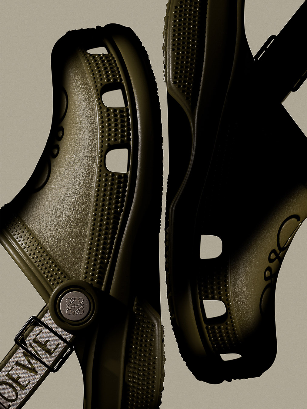 Close-up product shot of two olive green Crocs sandals featuring the Loewe brand logo on the instep strap and top of the clog.