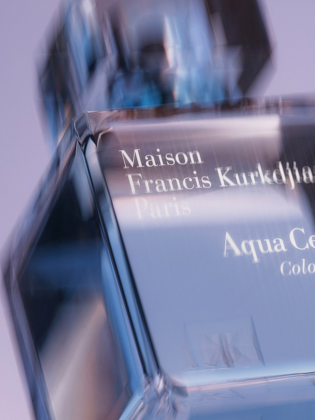 Close-up studio shot of a transparent glass perfume bottle with text reading 'Maison Francis Kurkdjian Paris Aqua Celestia Cologne'.