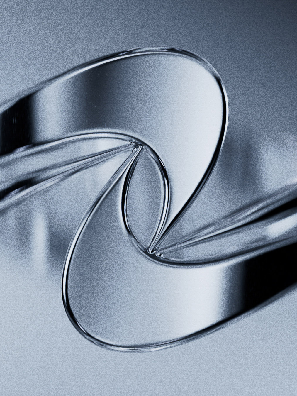 Abstract macro photograph of a transparent twisted object with reflective surfaces and a cool color palette against a light grey background.