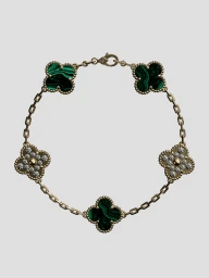Van Cleef & Arpels gold chain bracelet with green malachite and diamond four-leaf clover motifs on a neutral background.